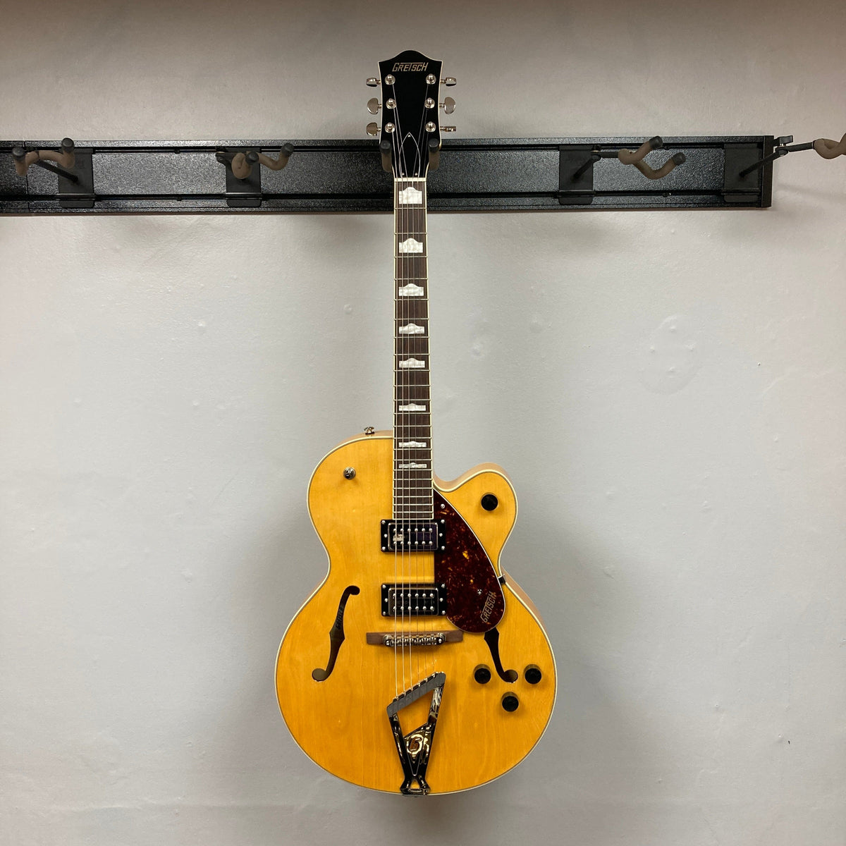 Gretsch G2420 Village Amber Used guitar on a stand, showcasing its hollowbody design and classic aesthetic with F-holes and Broad'Tron humbuckers.