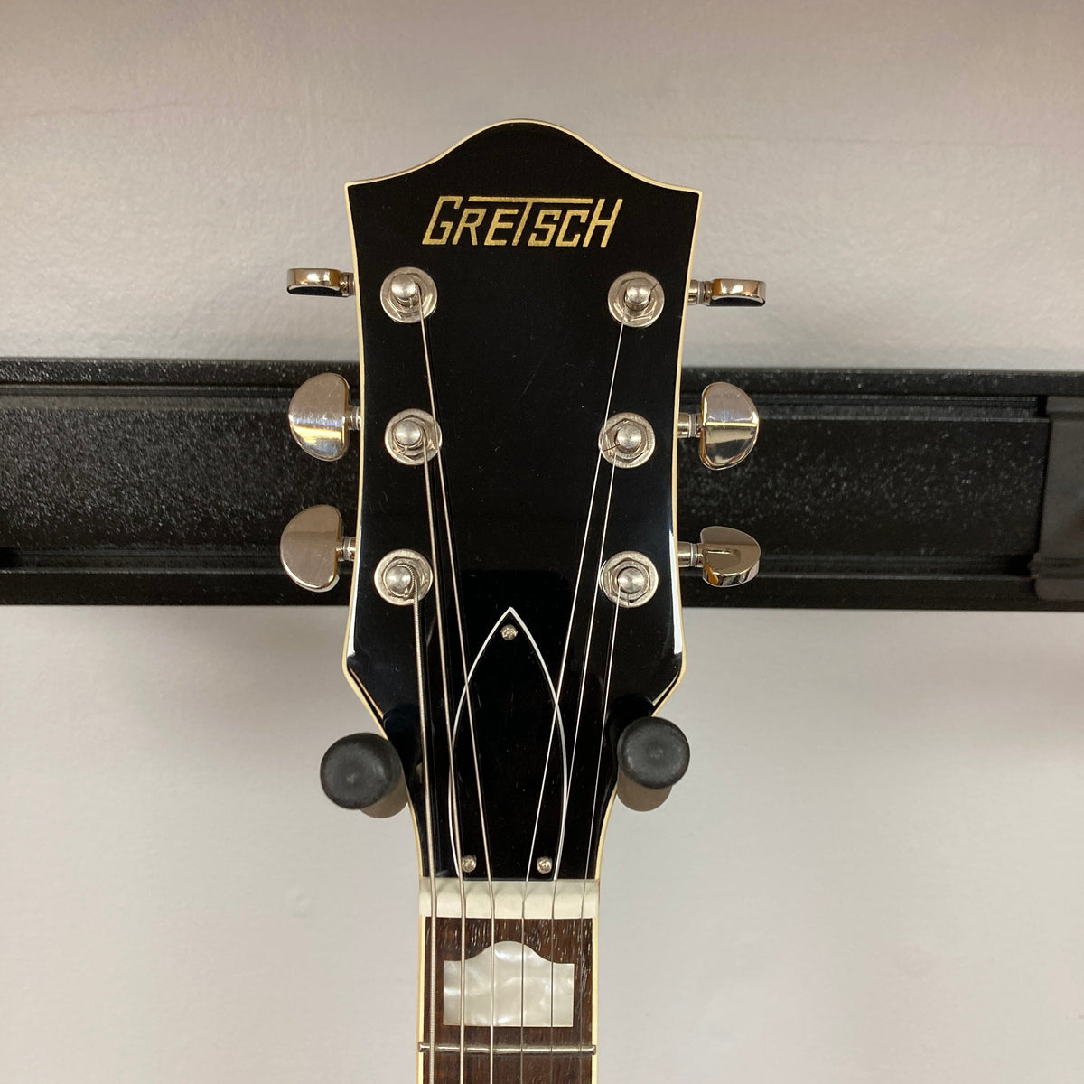 Gretsch G2420 Village Amber Used guitar, featuring hollowbody design, Broad'Tron humbuckers, and classic aesthetic, hanging on a wall.