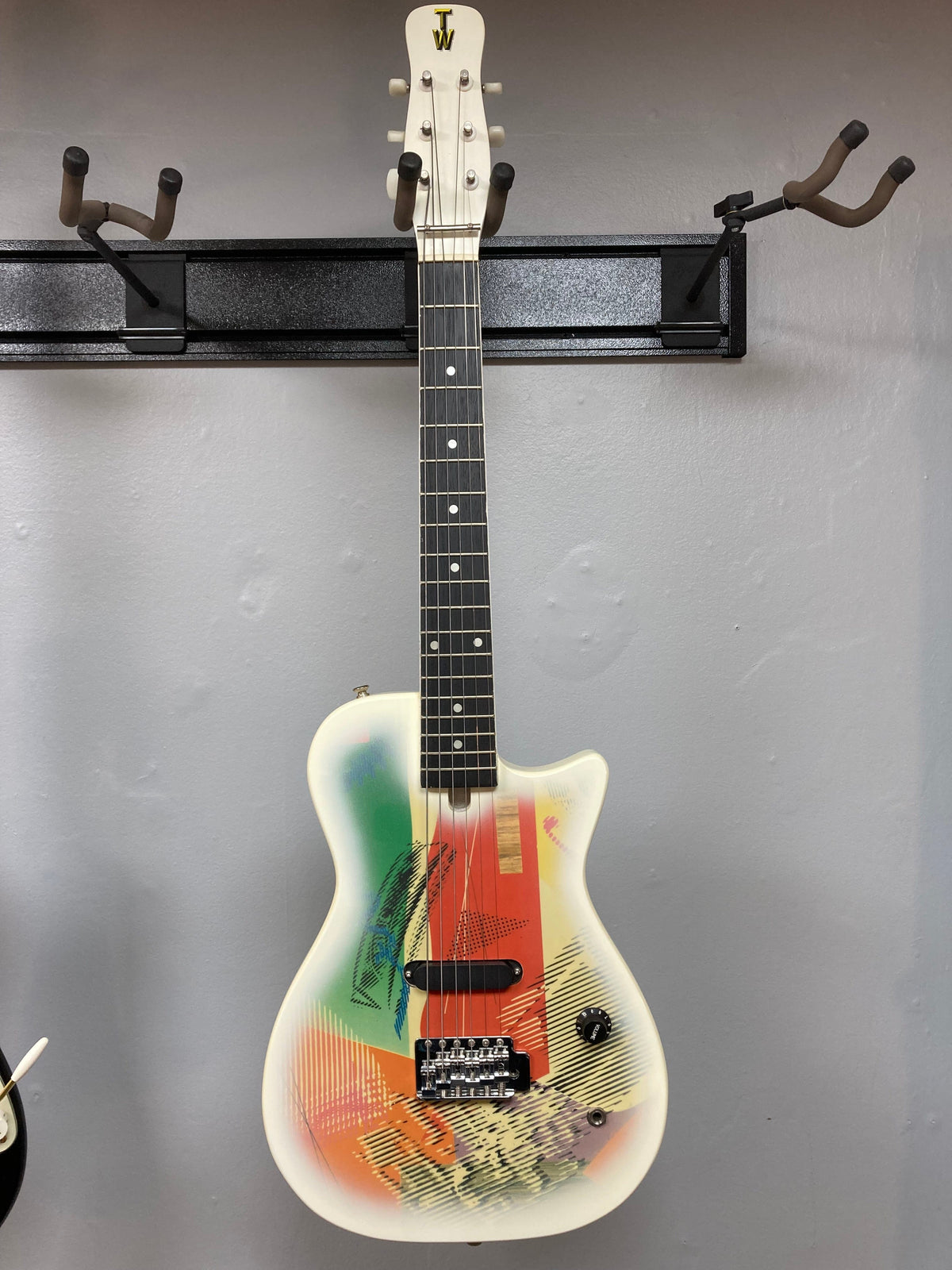 Gretsch Traveling Wilburys TW-100T Electric Guitar with colorful design, displayed on a wall.