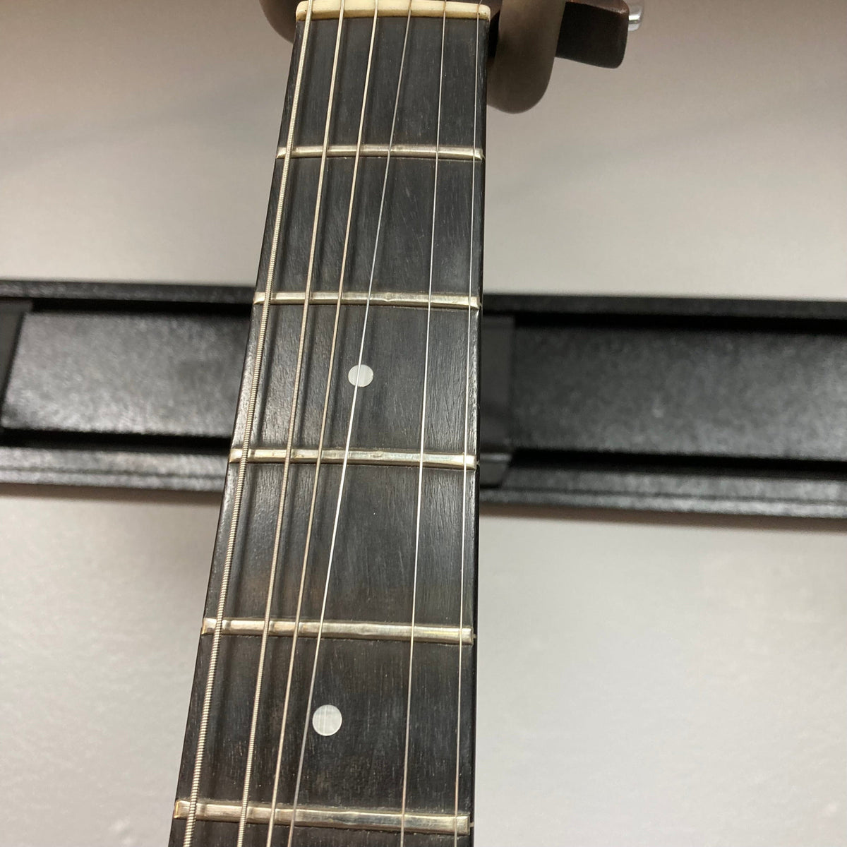 Close-up of a Guild USA X-79 Candy Apple Red guitar neck with case, showcasing its 24-fret fingerboard and unique design.