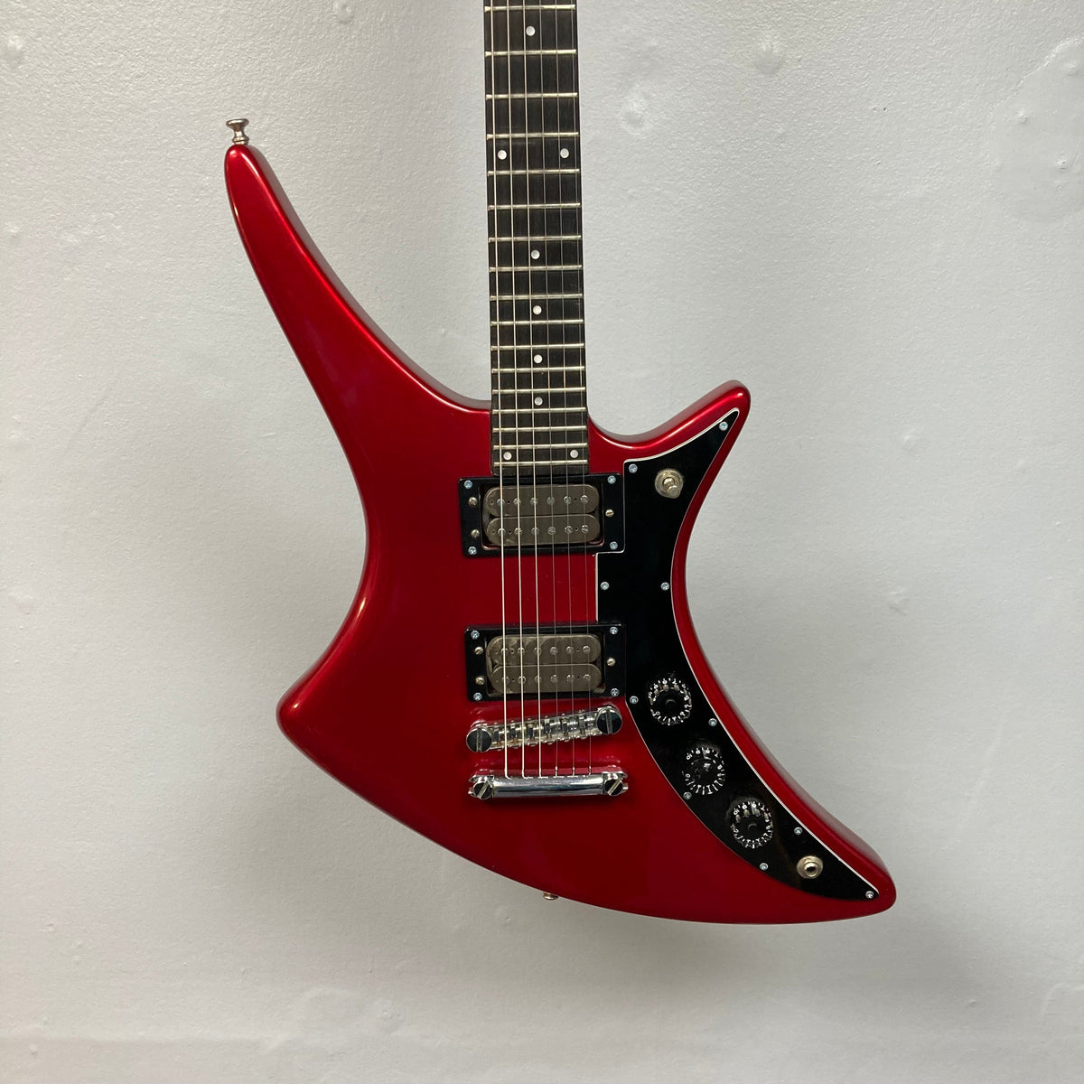 Guild USA X-79 Candy Apple Red electric guitar with 24-fret fingerboard, displayed on a wall.