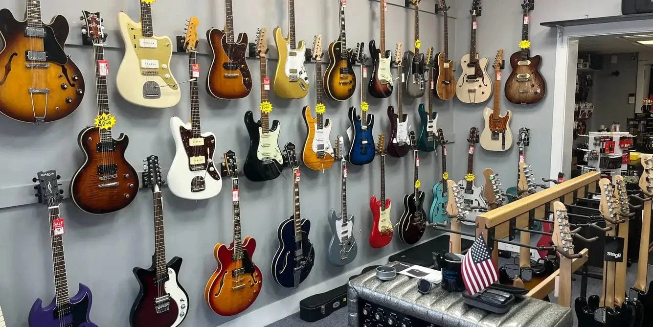 Wall display of various guitars in a store