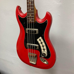 Hagstrom HII-B Mid-1960s Red Medium-Scale Bass with black pickguard, dual pickups, chrome bridge, leaning against a wall, showcasing vintage Scandinavian design.