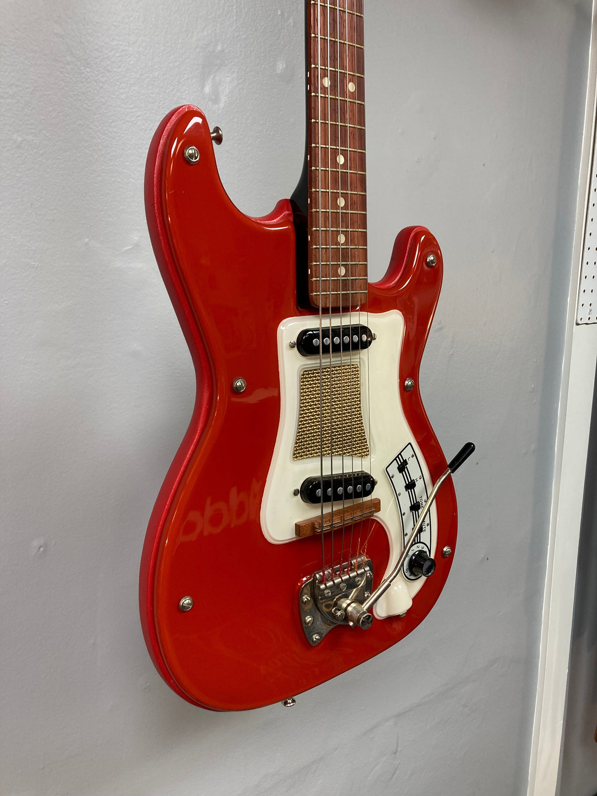 Hagstrom I vintage electric guitar with original case, featuring a deep red finish and minimal player's wear, displayed on a wall.