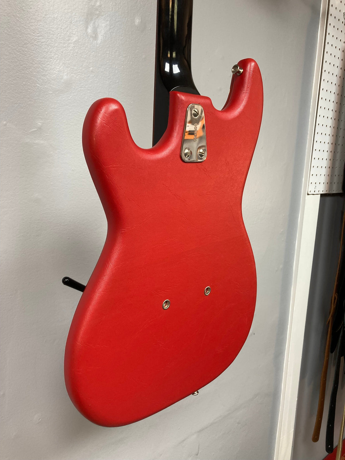 Hagstrom I vintage red electric guitar with silver hardware, displayed on a wall.