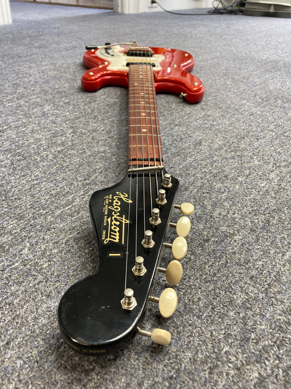 Hagstrom I Vintage Electric Guitar with original case, red and white, minimal wear, flatwound strings, on grey carpet.