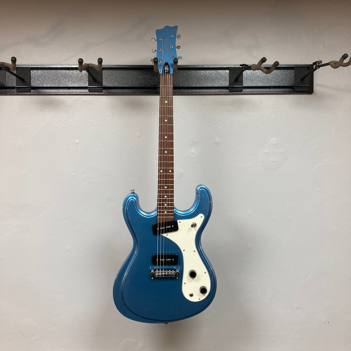 Harley Benton MR-Classic Vintage Series Metallic Blue Gloss electric guitar mounted on a wall hook.