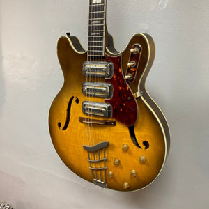 Harmony H-75 1960s Sunburst electric guitar with a sunburst finish, displayed on a wall, highlighting its elegant design and versatile tone.