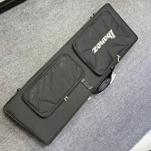 A black rectangular instrument case from Guitars on Main, ideal for the Ibanez JEM77P Steve Vai Signature electric guitar, sits on a gray carpeted floor and features two zippered pockets for convenience.