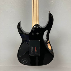 The back of a Guitars on Main Ibanez JEM77P Steve Vai Signature electric guitar shows access panels, a battery compartment, and the neck joint against a plain light-colored background.