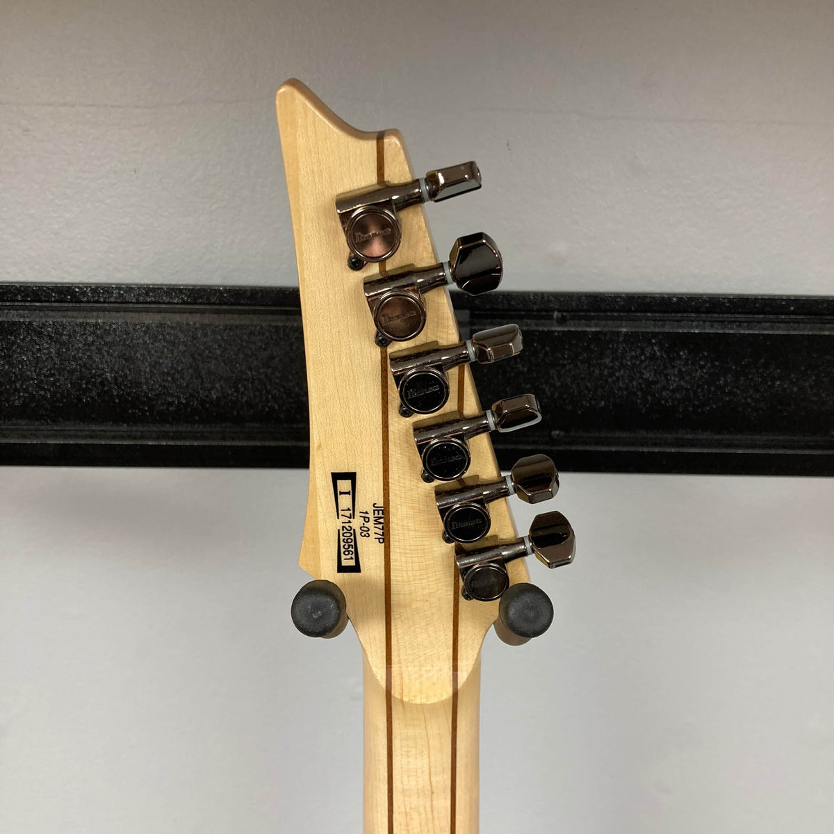 The back of a Guitars on Main Ibanez JEM77P Steve Vai Signature guitar headstock displays six metal tuners, a serial number, and manufacturer marks on light wood.