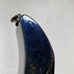 Close-up of the Ibanez Prestige RG1570 Cosmic Blue headstock, showcasing its shimmering dark blue finish with iridescent specks, a tuning peg, and a simple light background. Includes case.