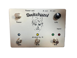 The Switchazel Boutique AB/Y Switcher with Tuner Out (Preowned) by Switchazel features five switches, indicator lights, and multiple I/O jacks on a metallic panel for seamless ground loop elimination.