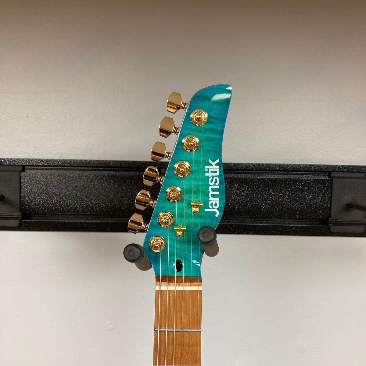 Jamstik Deluxe MIDI Blue Guitar on a stand, featuring 24 frets and full MIDI capabilities, with visible HH pickup configuration and a hard-shell case included.