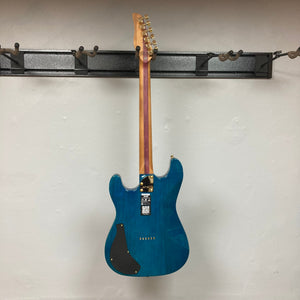 Jamstik Deluxe MIDI Blue Guitar w/Case, featuring 24 frets, HH pickups, and MIDI capabilities, displayed on a wall.