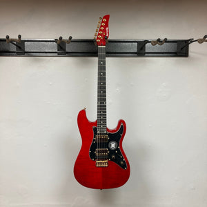 Jamstik Deluxe MIDI Red Black Guitar w/Case, displayed on a wall, showcasing its electric design and advanced MIDI features for professional and hobbyist musicians.