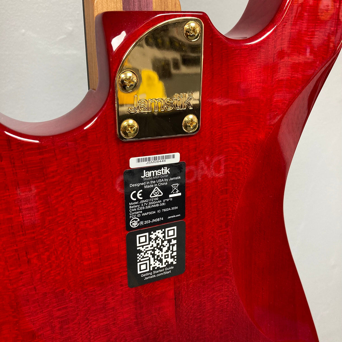 Back view of the Jamstik Deluxe MIDI Red Black Guitar w/Case, showcasing its metal plate, QR code, and detailed craftsmanship.