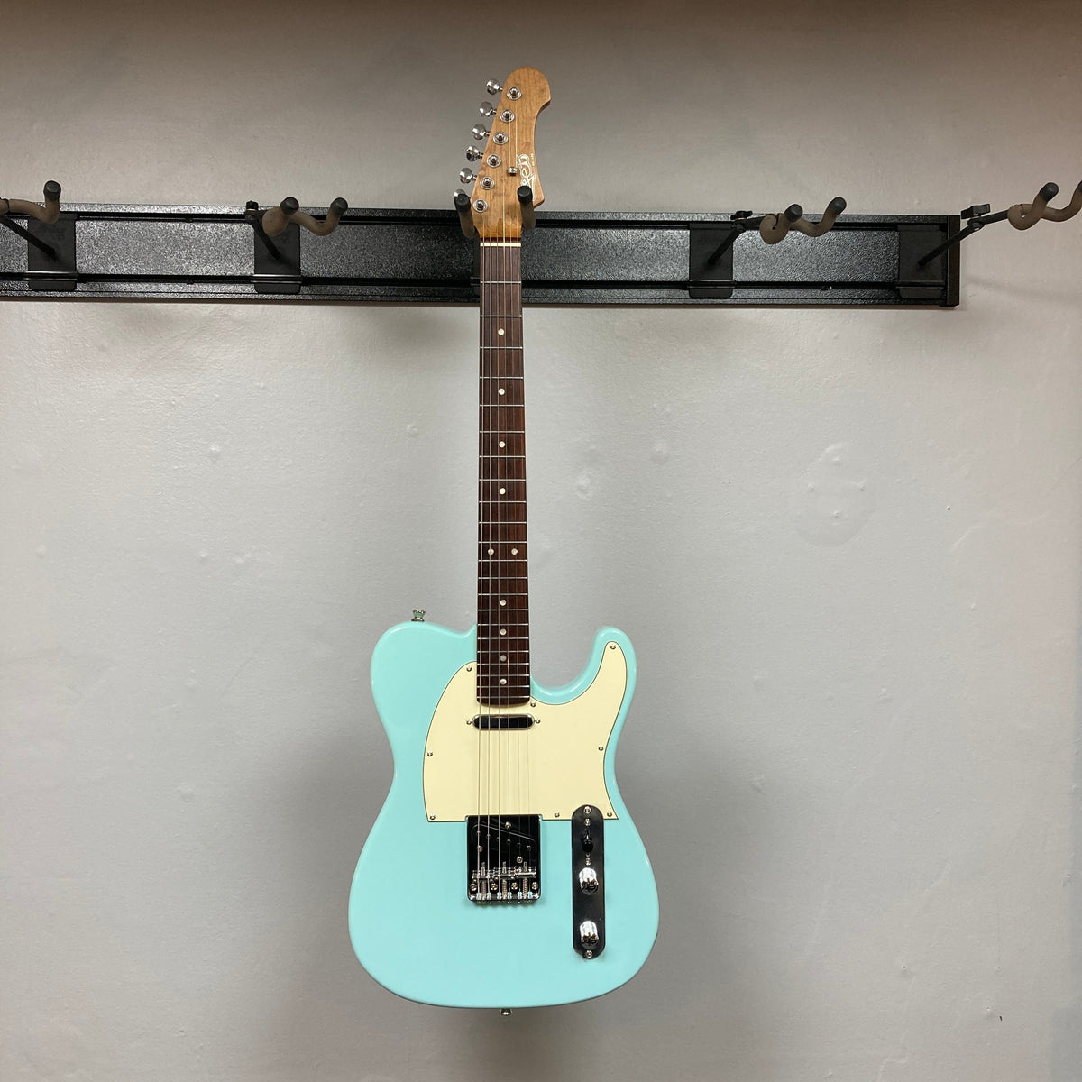 Jet JT-300 Guitar displayed on wall, featuring a blue electric design with brown neck and chrome hardware, showcasing quality craftsmanship and sound.