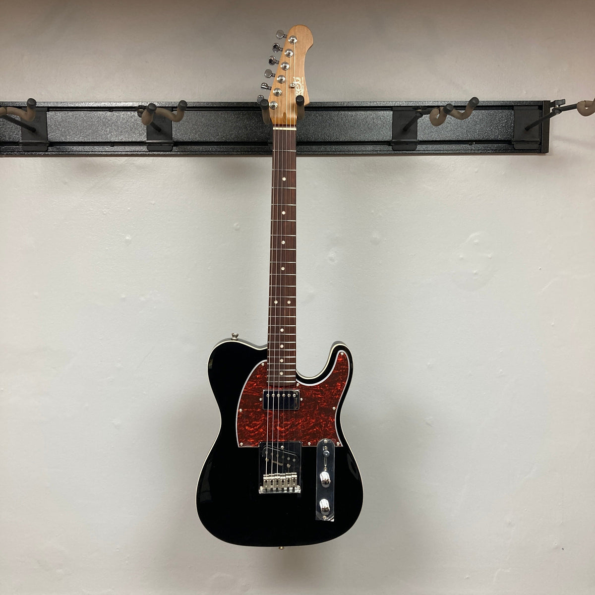 JET JT-350 electric guitar with black body and red specks, featuring a Canadian roasted maple neck and chrome hardware, hanging on a display hook.