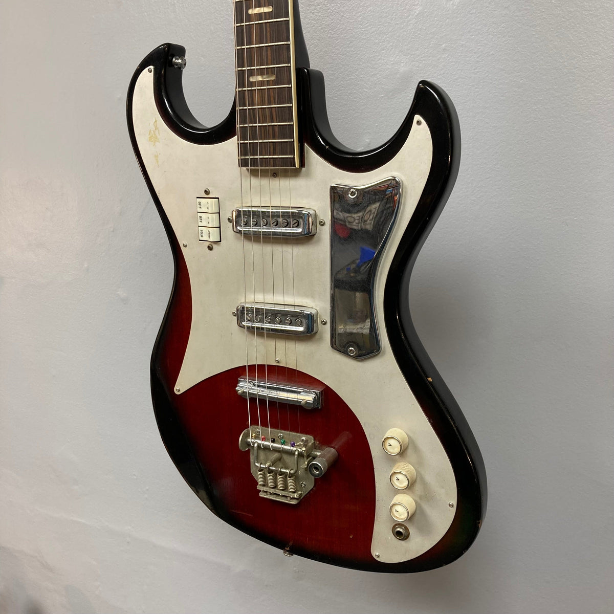 Kawai Vintage 1960s Kawai Teisco Japan Hound Dog Reburst guitar displayed on a wall, showcasing its unique vintage design and craftsmanship.