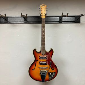 Kingston Semi-Hollowbody 1960's Vintage Burst guitar on a hook, showcasing its semi-hollow design and vintage aesthetic.