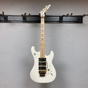 Kramer Jersey Star Pearl White electric guitar with gold hardware, star inlays, three humbucker pickups, Floyd Rose tremolo, and included gig bag.