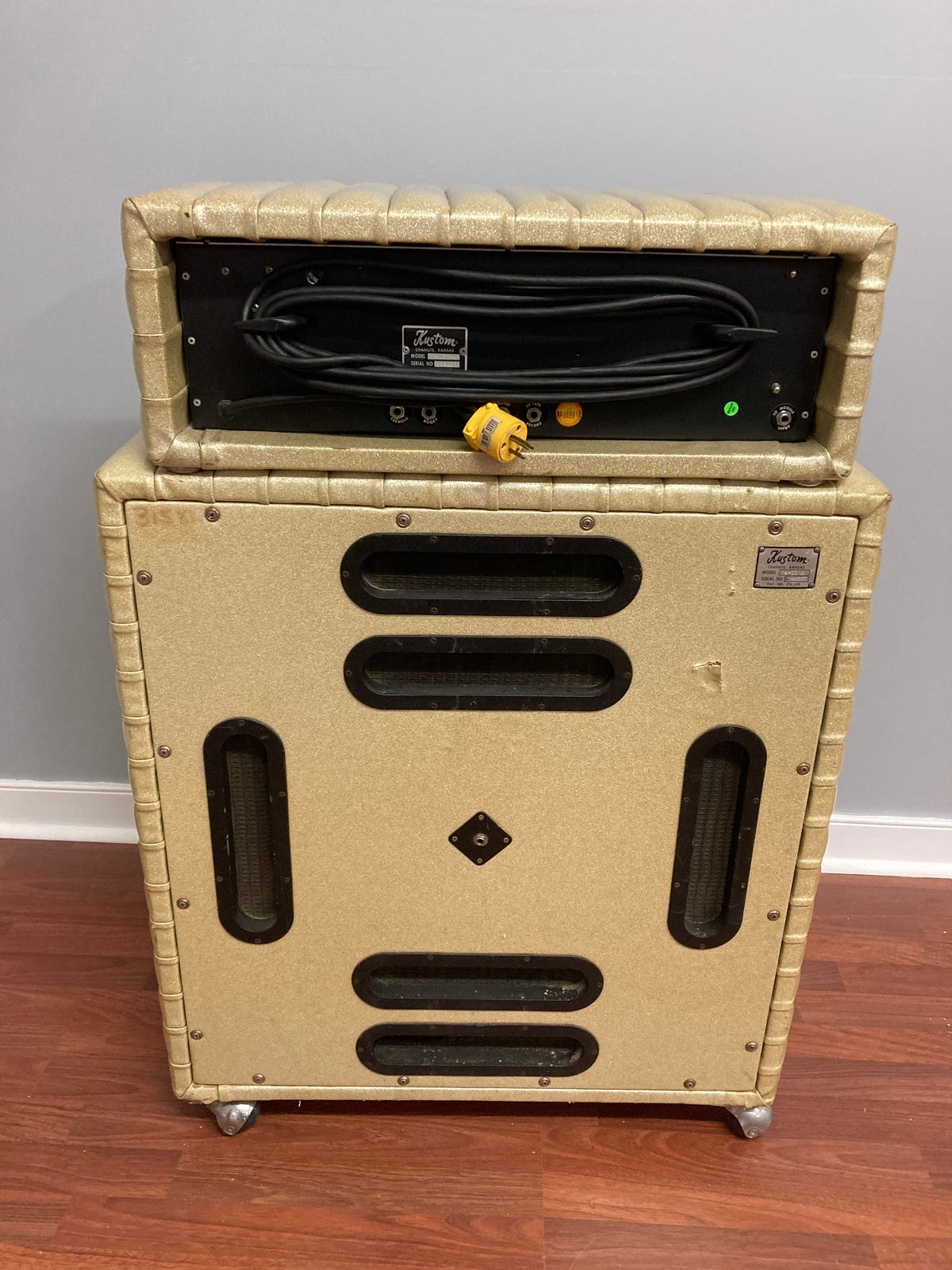 Kustom K250-4 Amp and Speaker Cabinet Gold Sparkle Tuck and Roll on a wooden floor, showcasing its vintage design and powerful sound features.