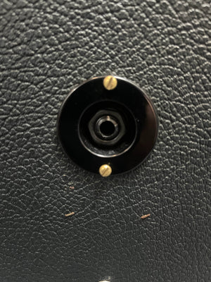 Close-up of a black audio jack socket with gold screws on a textured surface, as found on a 1969 Marshall 4x12 Cabinet with Matching Celestion T1281 Greenbacks.
