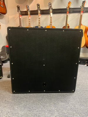 A 1969 Marshall 4x12 Cabinet with Matching Celestion T1281 Greenbacks sits in front of several acoustic guitars on display in a music store.