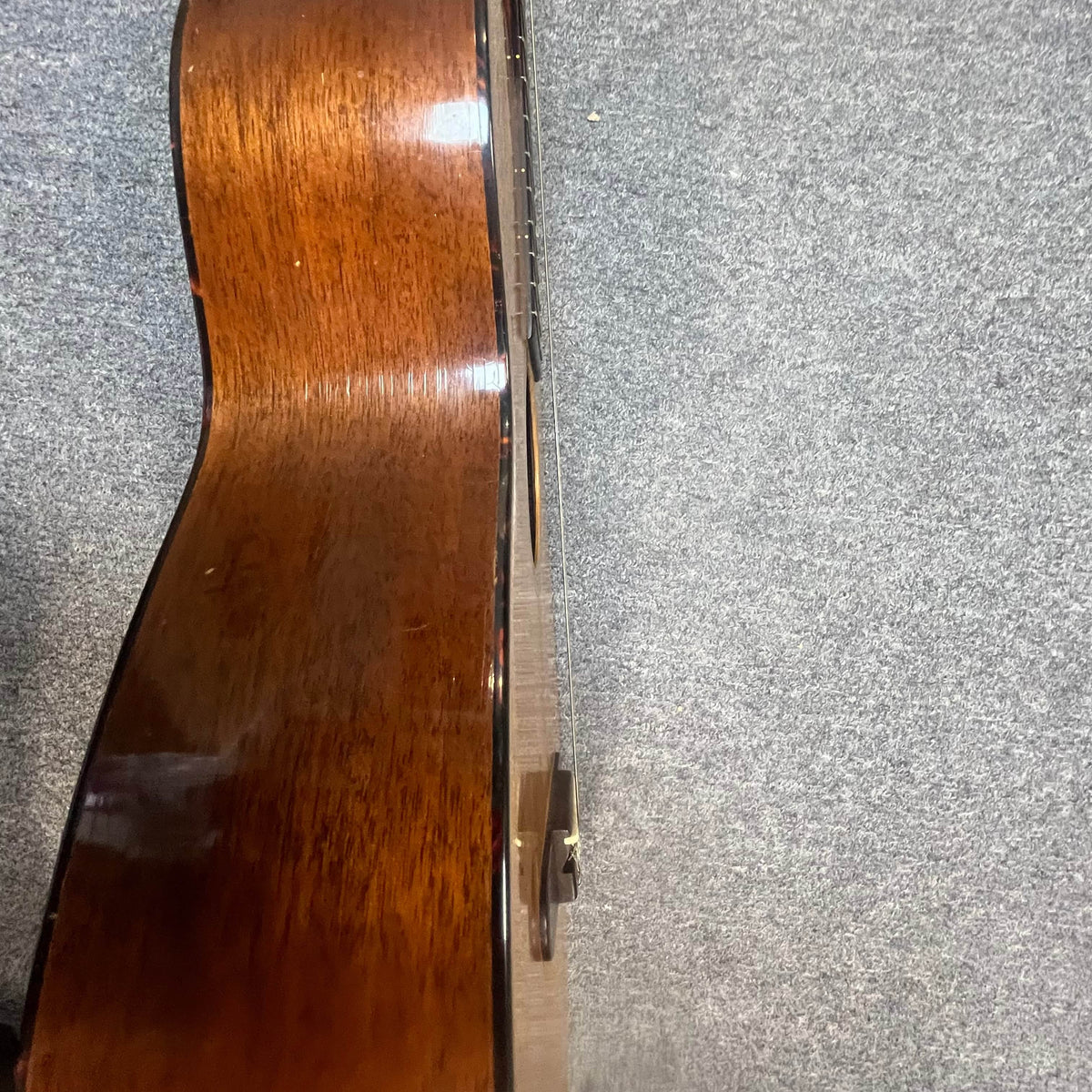 A Martin 00-18G Classical Guitar (c. 1961–1962) with nylon strings and a visibly warped neck rests on a gray carpeted floor.