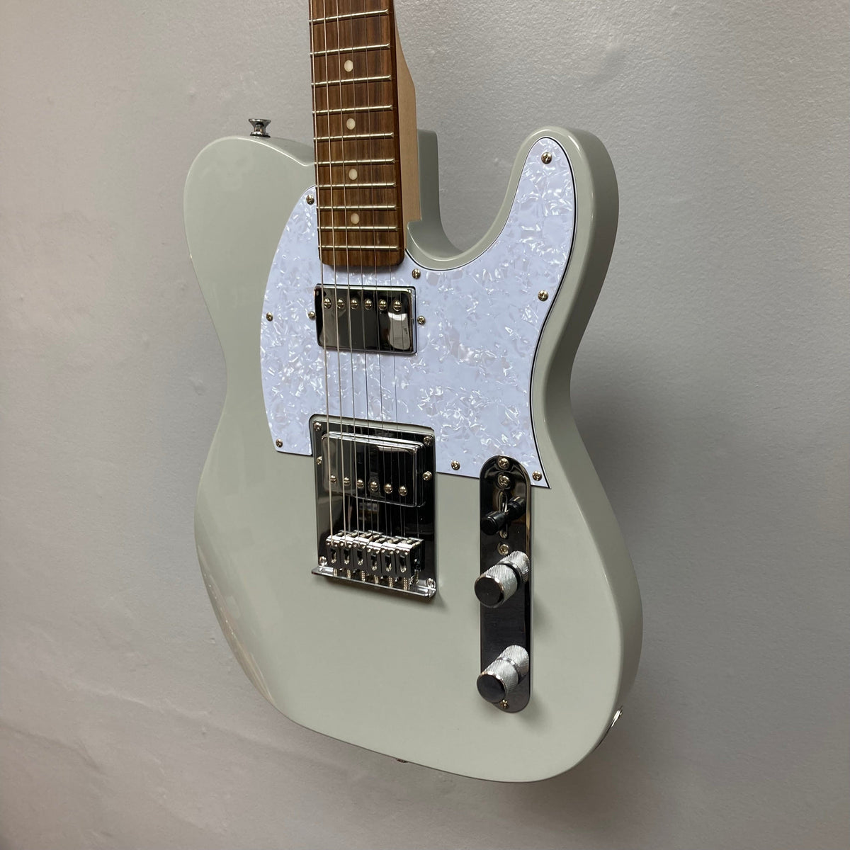 Michael Kelly 53 Tele Gloss Gray Prototype Demo, white electric guitar with double humbucker configuration, displayed on a wall.