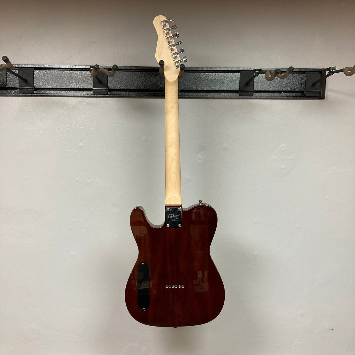 Michael Kelly 58 Tele Thinline Flame Maple Prototype Demo guitar on a wall hook, showcasing its semi-hollow body and dual Rockfield® SWC humbucker pickups.