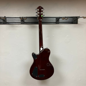 A Michael Kelly Hybrid Special Electric Guitar - Spalt Burst hangs by its neck on a black wall rack with its back facing outward against a plain white wall.