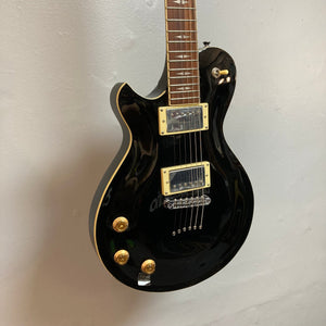 Michael Kelly Patriot Decree Lefty Black Blem, a black electric guitar with mahogany body and PAF pickups, mounted on a wall.