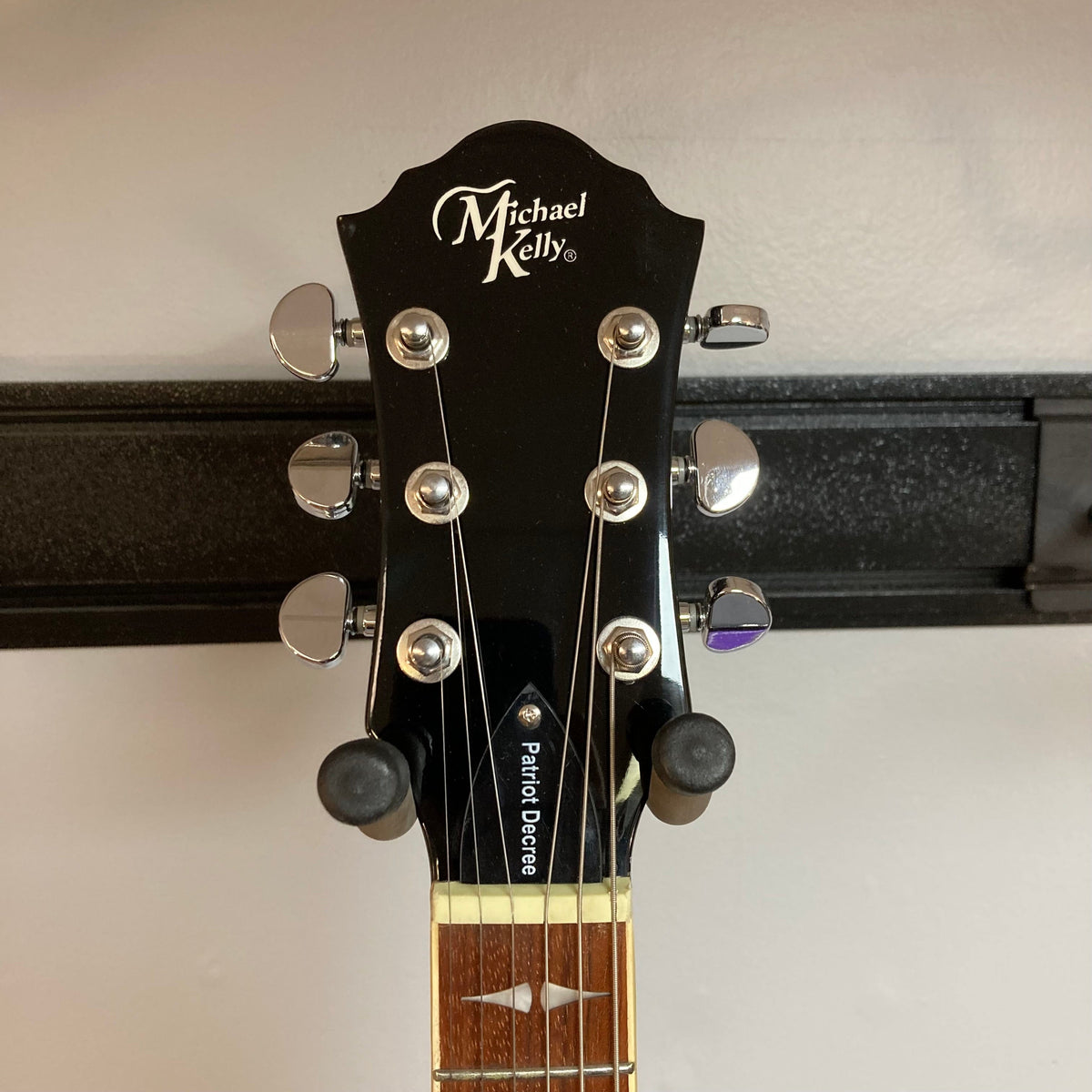 Close-up of the Michael Kelly Patriot Decree Lefty Black Blem guitar headstock and neck, showcasing tuning pegs and fretboard details.