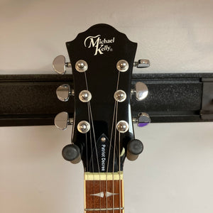 Close-up of the Michael Kelly Patriot Decree Lefty Black Blem guitar headstock and neck, showcasing tuning pegs and fretboard details.