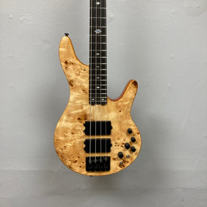 Close-up of the Michael Kelly Pinnacle 4 Bass guitar neck and strings, showing intricate fretboard inlays and dual humbucker pickups.