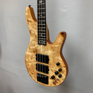 Close-up of the Michael Kelly Pinnacle 4 Bass guitar, showcasing its intricate burl poplar top, diamond inlays, and Rockfield MDC4 humbucker pickups.