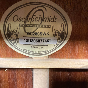 Close-up of an oval label inside a wooden Oscar Schmidt OU280SWK Concert Ukulele w/Case (Used Consign), showing serial number 01130607746 and text noting it was handcrafted in Indonesia.