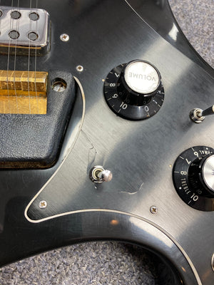 Ovation Deacon 12-String Electric Guitar, black, showing a close-up of the strings and dials with visible headstock chip and pickguard crack.