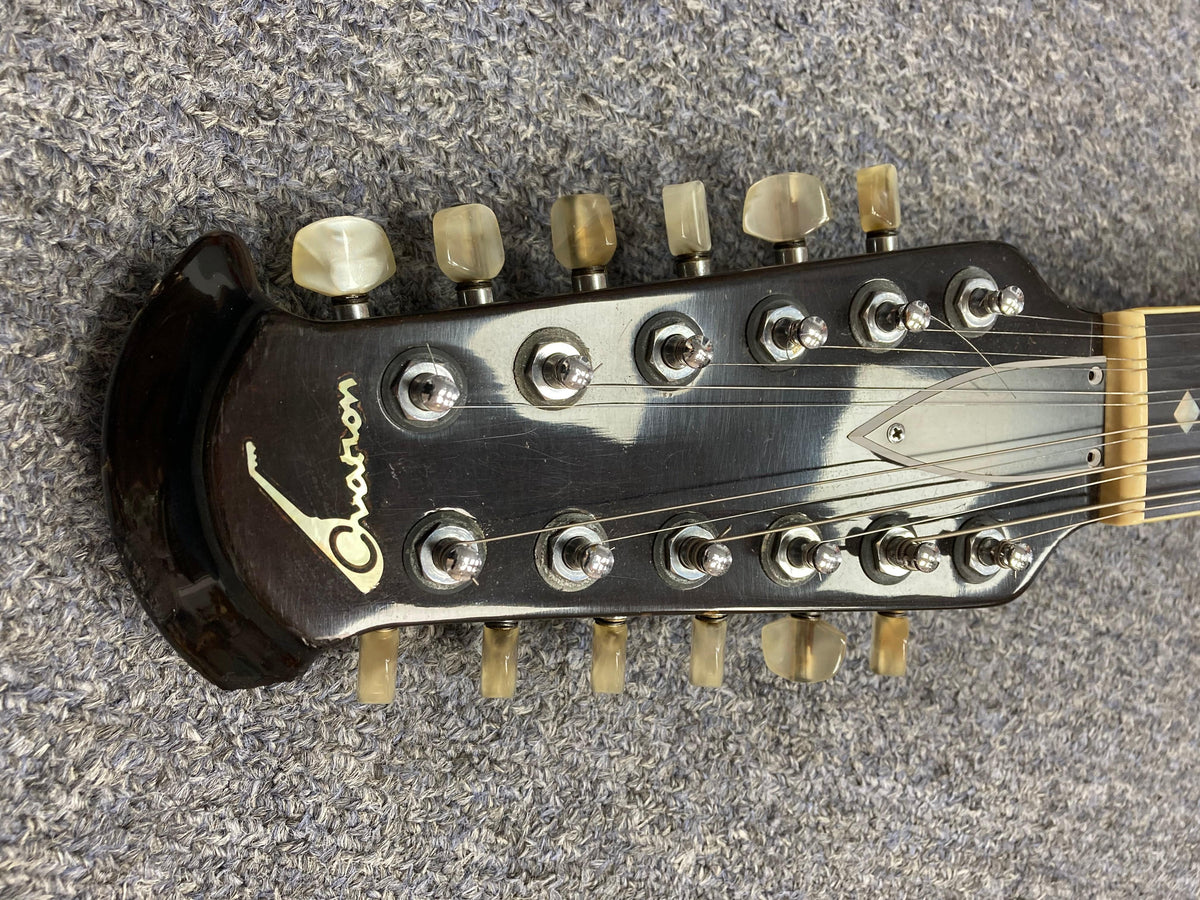 Ovation Deacon 12-String Electric Guitar headstock on a carpet, showcasing its vintage appeal and solid body design.