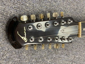 Ovation Deacon 12-String Electric Guitar headstock on a carpet, showcasing its vintage appeal and solid body design.