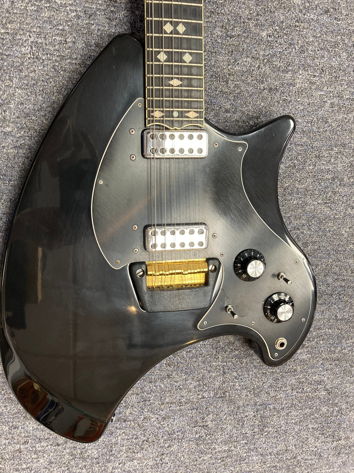 Ovation Deacon 12-String Electric Guitar in black, showcasing its solid body and distinctive features, including close-ups of strings and knobs, on a carpet background.