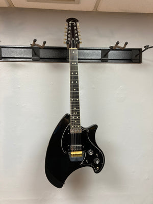 Ovation Deacon 12-String Electric Guitar in black, featuring a solid body with white diamond pattern on the neck, knobs, and switches.