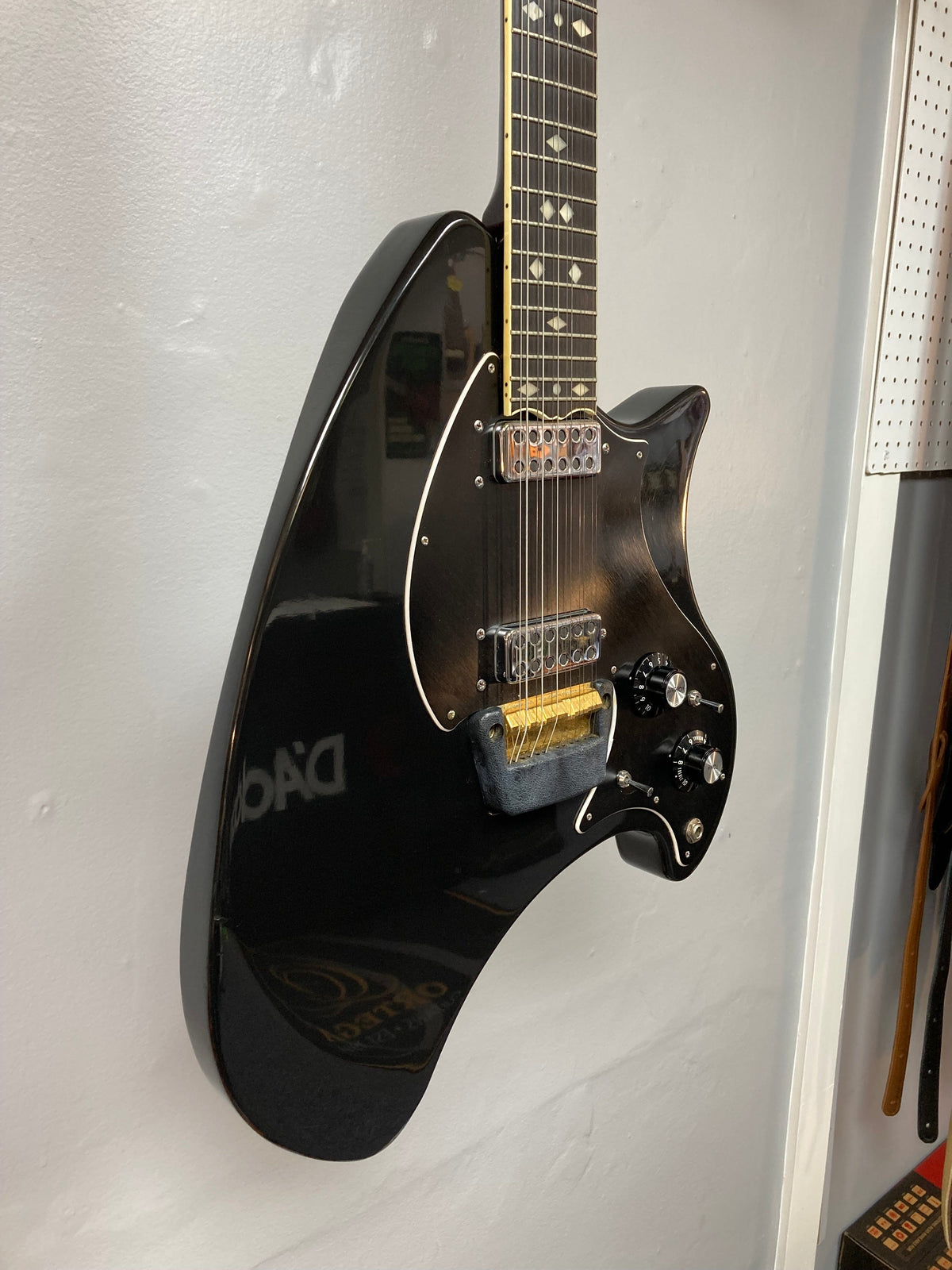 Ovation Deacon 12-String Electric Guitar in black, solid body, vintage era 1975-1980, minor headstock chip and pickguard crack, on a white wall.