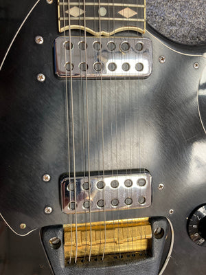 Ovation Deacon 12-String Electric Guitar in black, close-up showing strings and pickguard with minor cosmetic flaws.