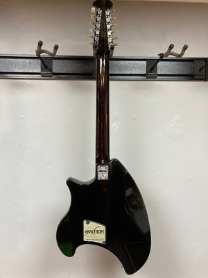Ovation Deacon 12-String Electric Guitar in black displayed on a stand, showcasing its solid body and vintage charm.