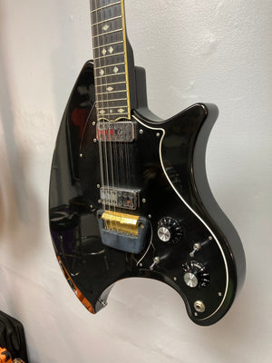 Ovation Deacon 12-String Electric Guitar in black, featuring knobs, switches, and visible string details, mounted on a wall.