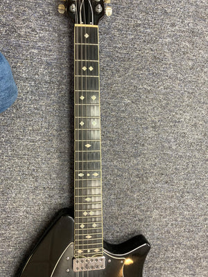 Ovation Deacon 12-String Electric Guitar in black on a carpet, showcasing its strings and body.