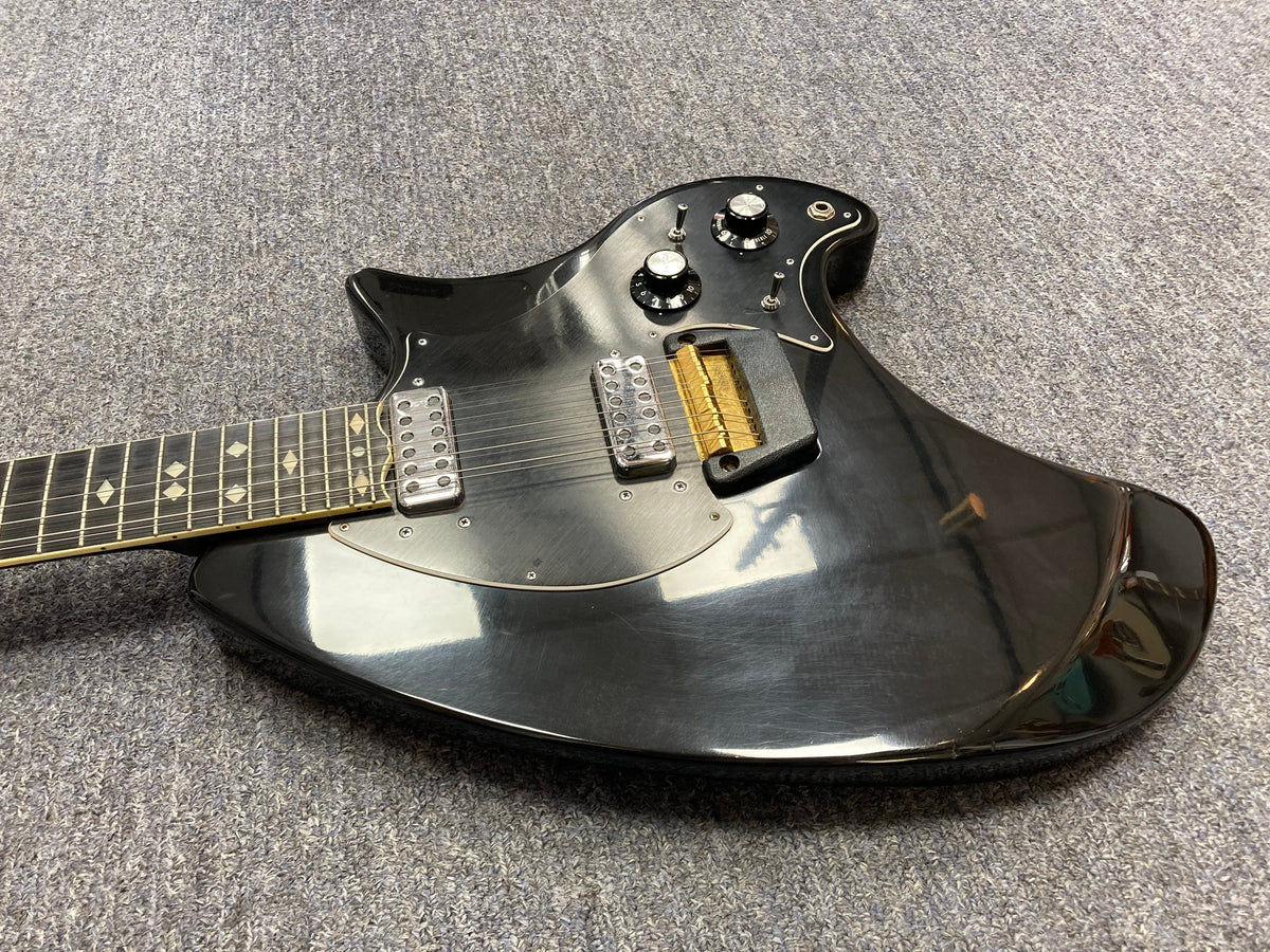 Ovation Deacon 12-String Electric Guitar in black, displayed on a grey carpet, highlighting its vintage solid body and distinctive knobs.